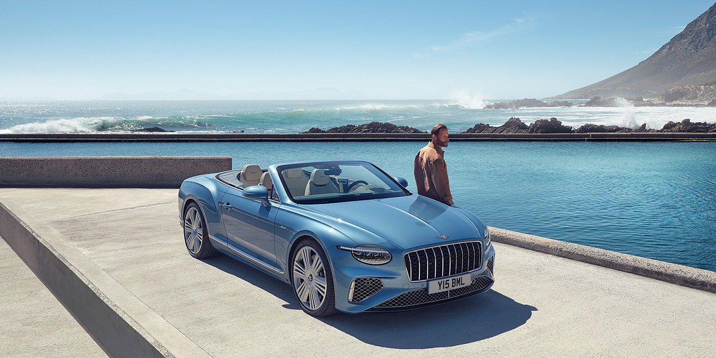 JCT600 Service Teeside New Bentley Continental GTC Azure convertible front view in Light Windsor blue paint with 22 inch ten spoke wheels parked by the sea in the sunshine