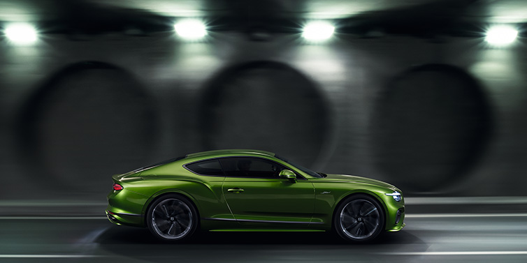 JCT600 Service Teeside Bentley Continental GT Speed coupe profile in Tourmaline Green driving dynamically past a concrete wall at night