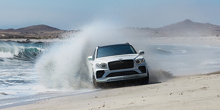 JCT600 Service Teeside Bentley Bentayga Speed SUV facing front in Snow Quarts Pearlescent white paint driving dynamically on beach