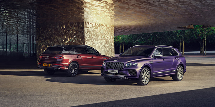 JCT600 Service Teeside A duo of Bentley Bentayga Extended Wheelbase Mulliner SUVs parked in a city environment, with Tanzanite Purple and Cricket Ball red exterior paint