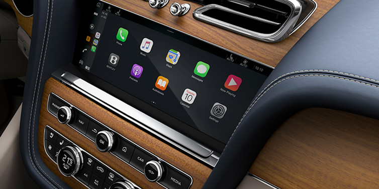 JCT600 Service Teeside Bentley Bentayga Azure SUV front interior console with MMI screen showing apps, surrounded by Imperial Blue and Portland hides, and Open Pore Koa veneer
