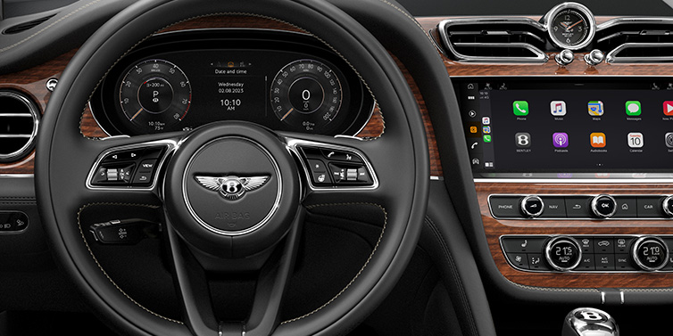 JCT600 Service Teeside Bentley Bentayga SUV front interior detail of steering wheel and driver screens surrounded by Beluga black hide and Crown Cut Walnut veneer
