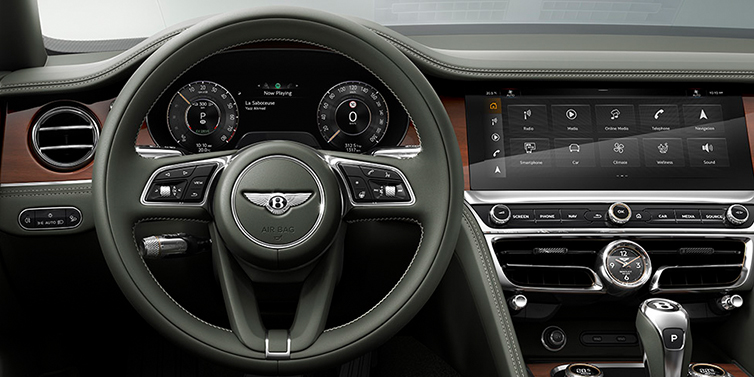 JCT600 Service Teeside New Bentley Flying Spur front cabin interior in Cumbrian green hide with Crown Cut walnut veneer showing steering wheel and driver controls