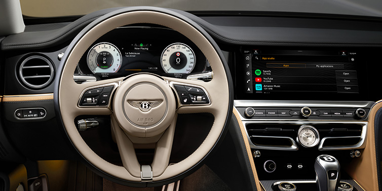 JCT600 Service Teeside Bentley Flying Spur Mulliner sedan front interior detail of steering wheel and driver screens surrounded by Linen and Beluga black hides