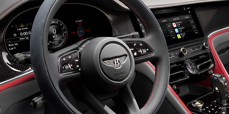 JCT600 Service Teeside Bentley Flying Spur Speed sedan front interior detail showing steering wheel and driver screens surrounded with Hotspur red and Gravity Grey hides